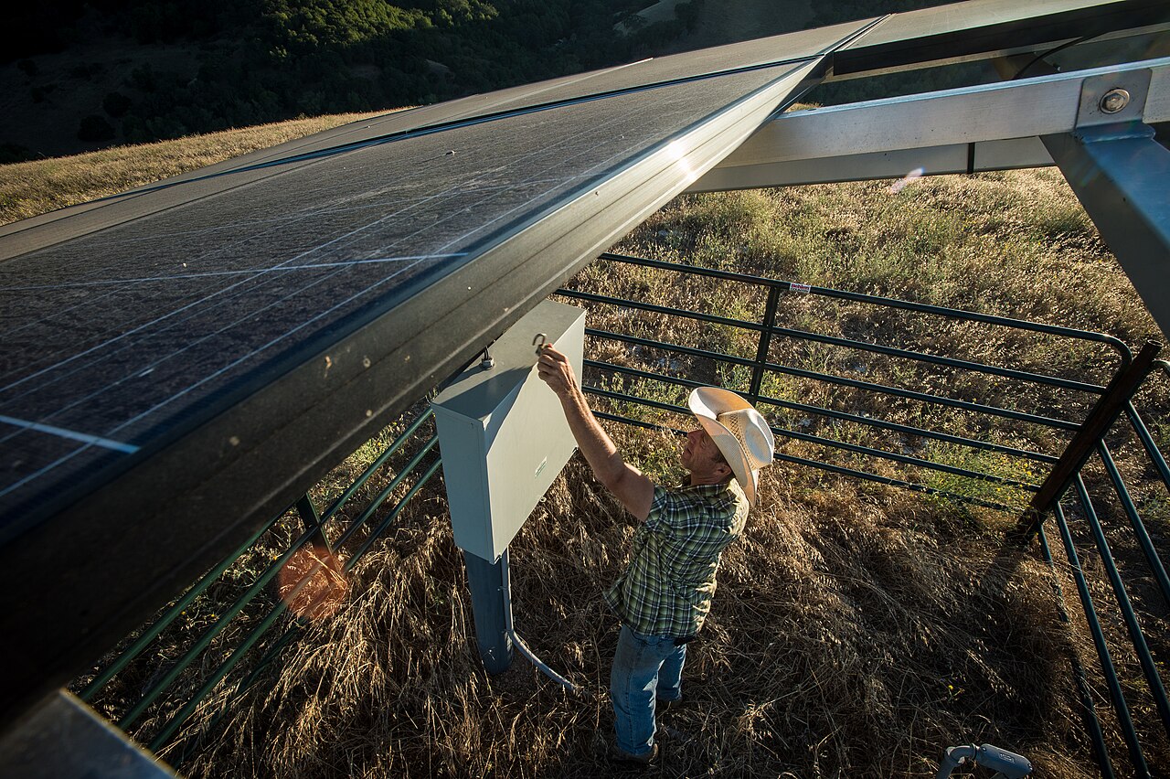 Technician working on a solar powered water pump installation in a field